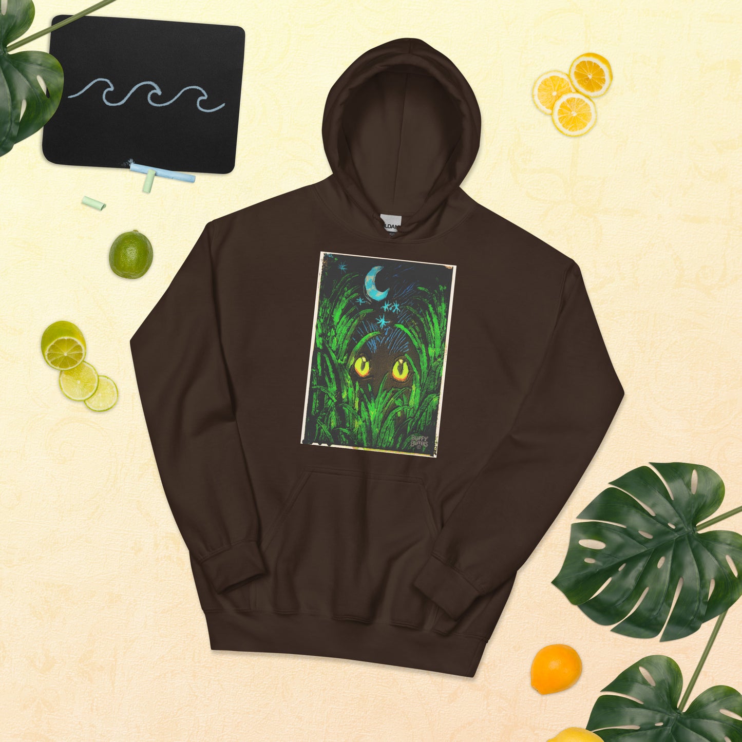 Dark chocolate unisex hoodie featuring "Midnight Watcher" artwork – glowing yellow eyes in green grass under a crescent moon (Canva Collection)