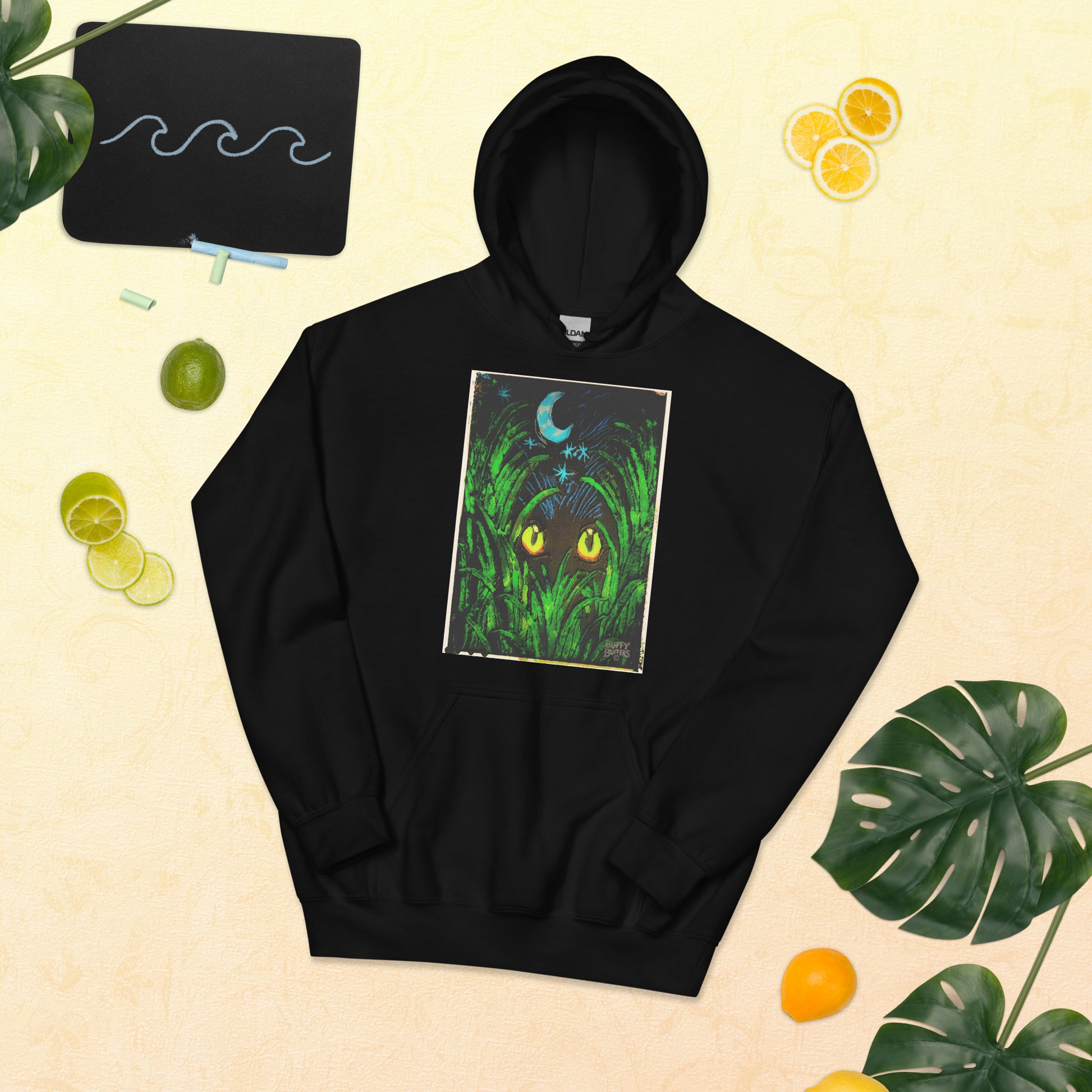 Black Unisex Hoodie with "Midnight Watcher" artwork – glowing yellow eyes in green grass under a crescent moonProduct mockup (Canva Collection)