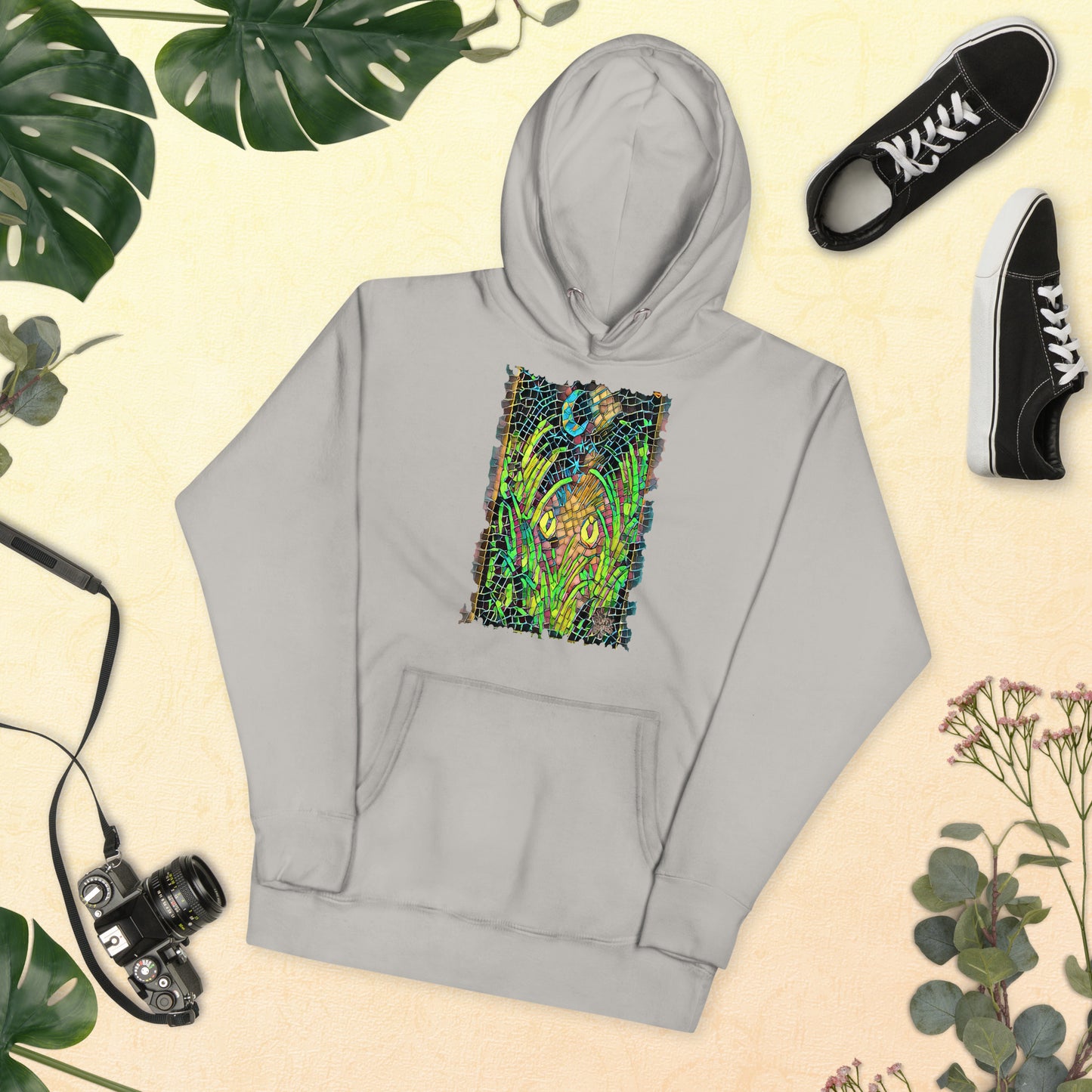Carbon grey unisex hoodie featuring “Midnight Watcher” artwork in Amber Collection mosaic style (glowing yellow eyes in green grass under a crescent moon)