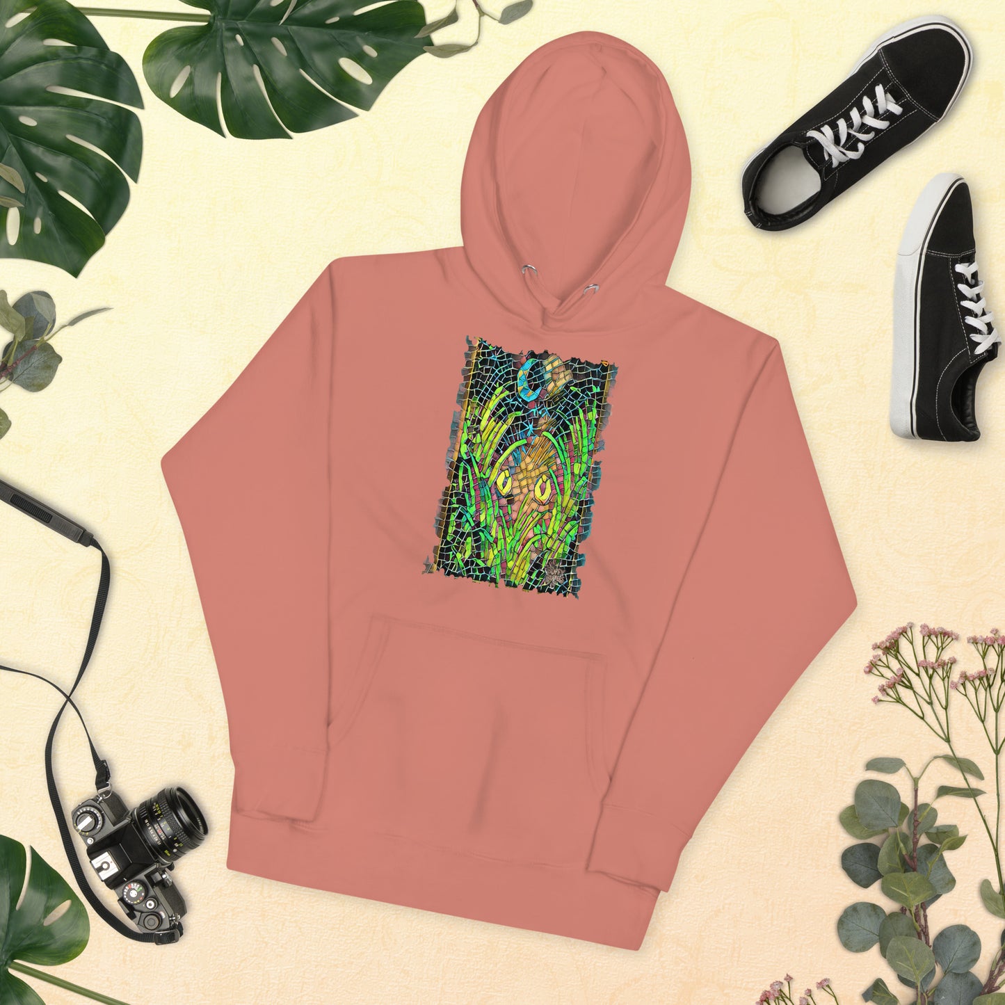 Dusty rose unisex hoodie featuring “Midnight Watcher” artwork in Amber Collection mosaic style (glowing yellow eyes in green grass under a crescent moon)