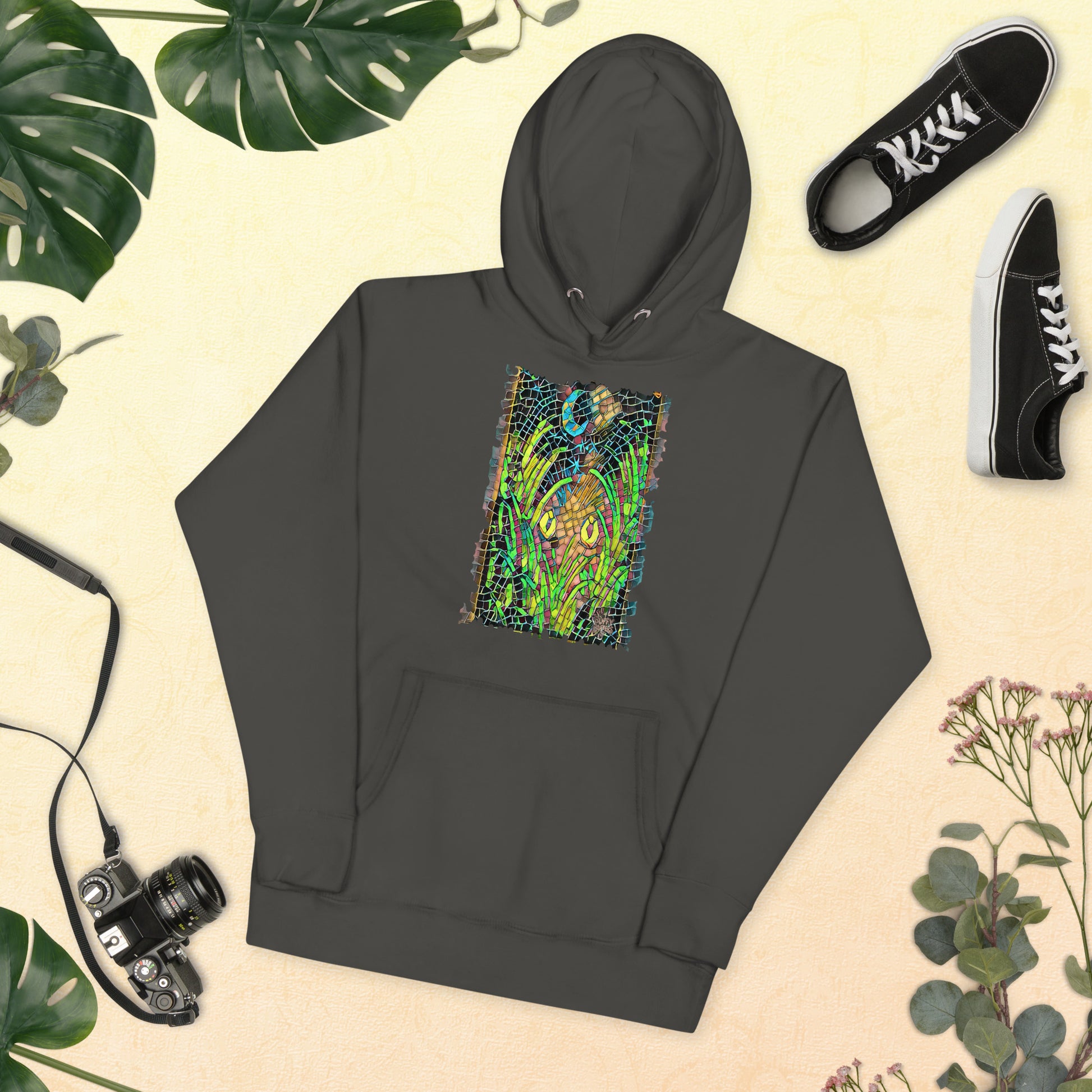 Vintage black unisex hoodie featuring “Midnight Watcher” artwork in Amber Collection mosaic style (glowing yellow eyes in green grass under a crescent moon)