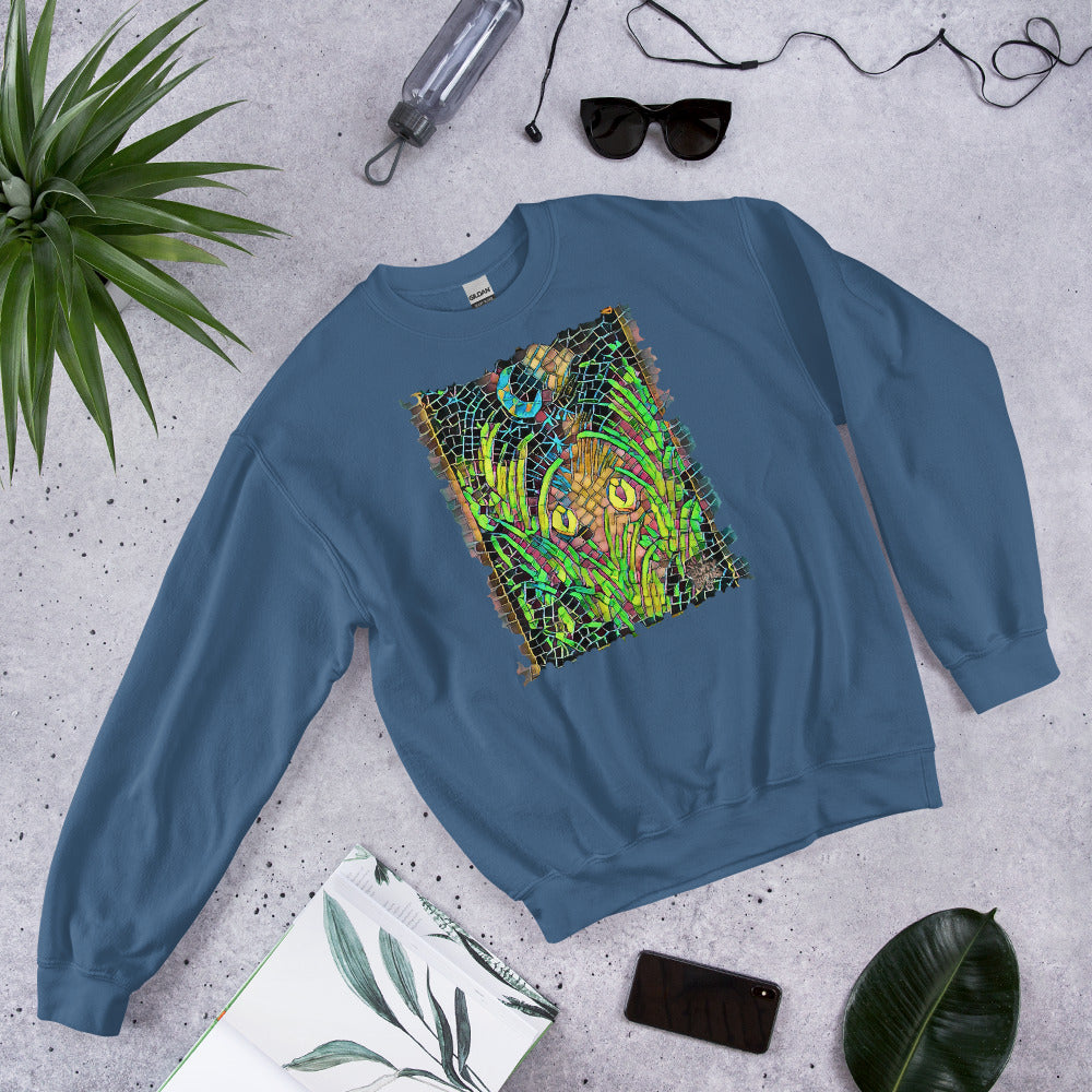 Indigo blue unisex sweatshirt featuring “Midnight Watcher” artwork in Amber Collection mosaic style (glowing yellow eyes in green grass under a crescent moon)