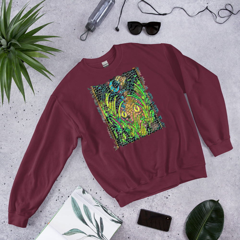 Maroon unisex sweatshirt featuring “Midnight Watcher” artwork in Amber Collection mosaic style (glowing yellow eyes in green grass under a crescent moon)
