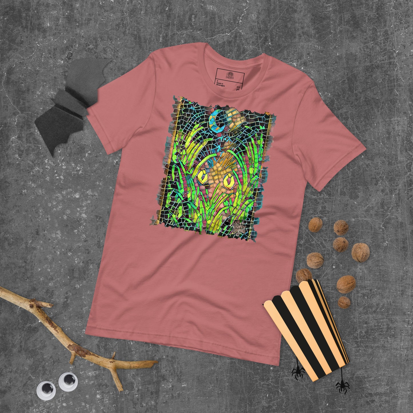 Mauve unisex t-shirt featuring “Midnight Watcher” artwork in Amber Collection mosaic style (glowing yellow eyes in green grass under a crescent moon)