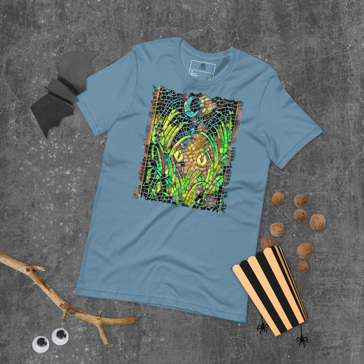 Steel blue unisex t-shirt featuring “Midnight Watcher” artwork in Amber Collection mosaic style (glowing yellow eyes in green grass under a crescent moon)
