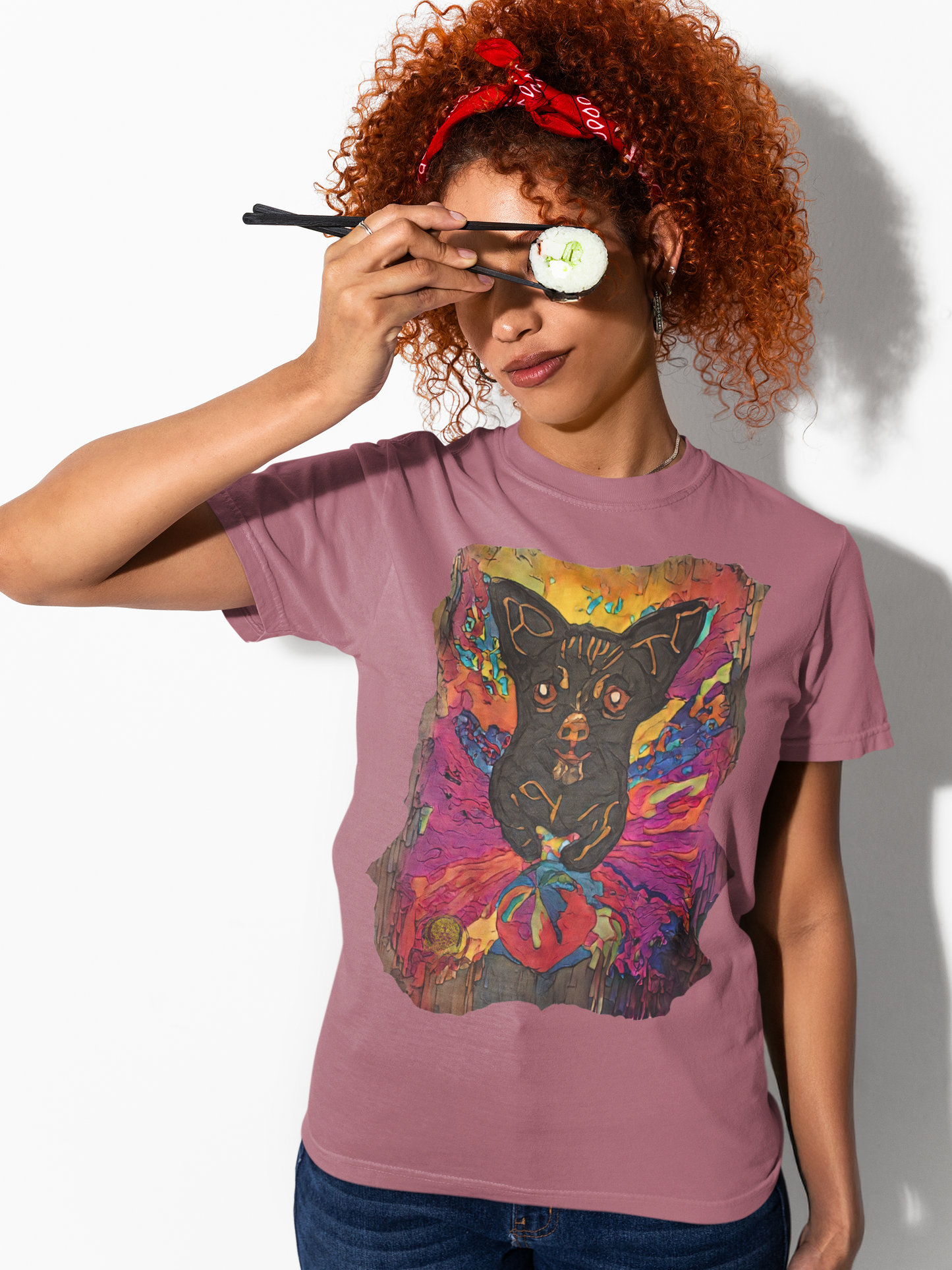 Person wearing a pink t-shirt with a colorful design, holding a makeup brush to their eye.